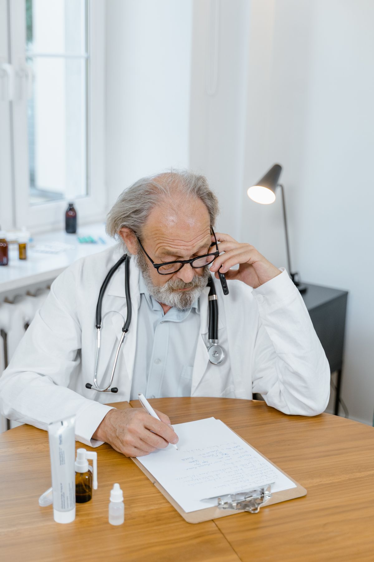 Frustrated doctor on the phone reviewing the paperwork from a stalled medical practice sale